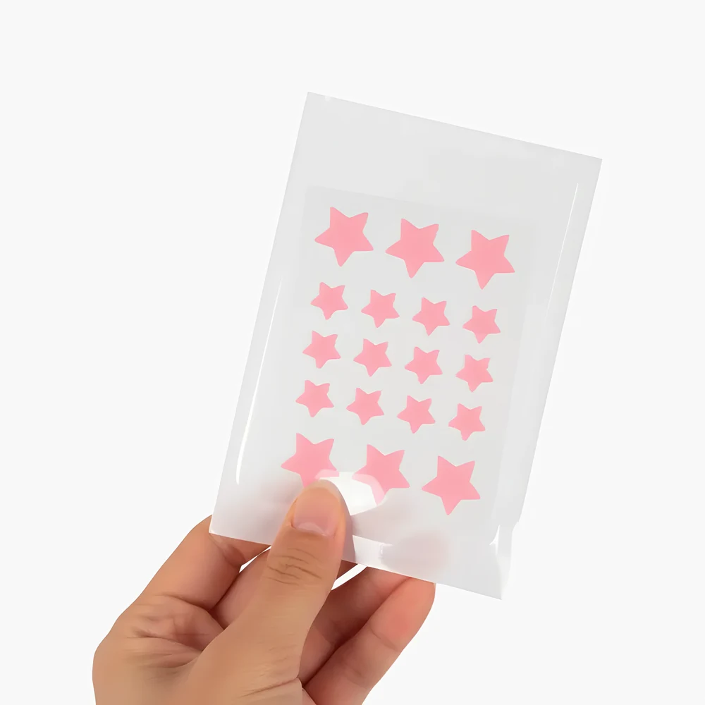 Mano sosteniendo el empaque de Kara Pimple Patch, mostrando la lámina con los parches hidrocoloides en forma de estrella